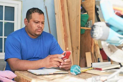 Latin man checking orders on cell phone Stock Photos