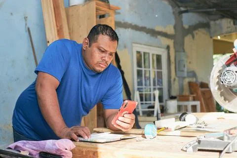 Latin man checking orders on cell phone Stock Photos