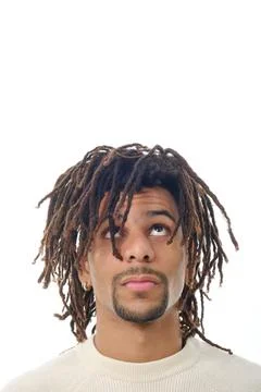 Latin man with dreadlocks looking up while standing against an isolated Stock Photos