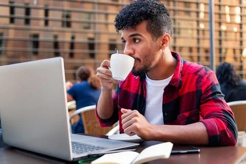 Latin man drinks coffee while working on a terrace Stock Photos