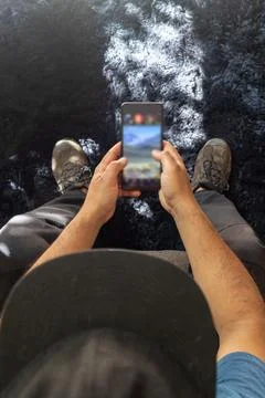 Latin man sitting down checking his social media on his cell phone, seen fr.. Stock Photos