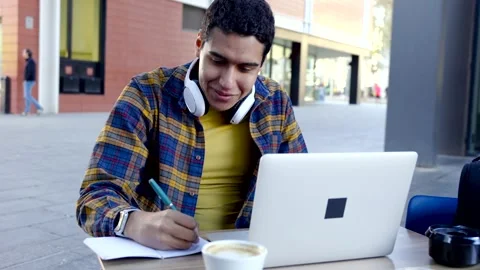 Latin man studying on s sidewalk cafeteria in the morning Stock Footage 258326352