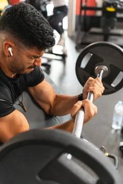Latin man suffering while lifting the Z-bar in the gym Foto stock
