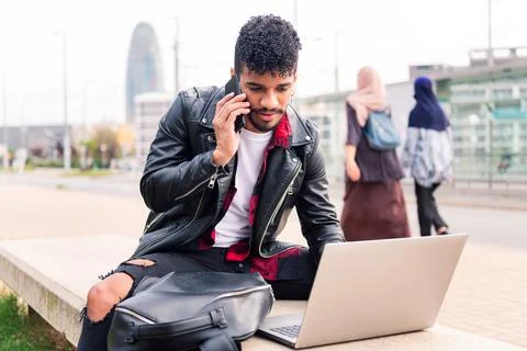 Latin man typing on computer and talking on phone Stock Photos