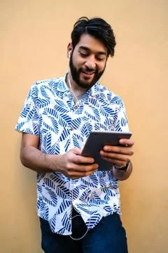 Latin man using his digital tablet with earphones. Stock Photos