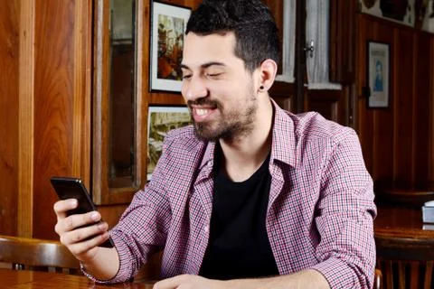 Latin man using his smartphone at a cafe. Stock Photos
