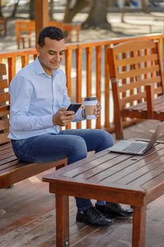 Latin man using a laptop while drinking coffee in a bar. 스톡 사진