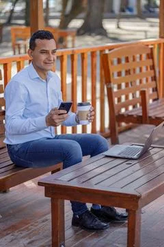 Latin man using a laptop while drinking coffee in a bar. Photos