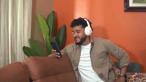Latin man using mobile phone listening music with headphones Stock Footage 338400781