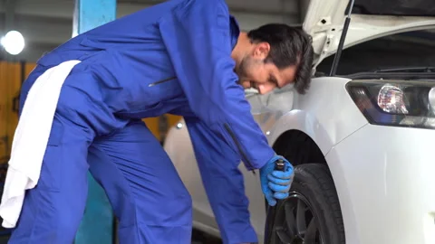 Latin mechanic worker checking car replacing wheel and tyre in auto repair .. Stock Footage 269762054