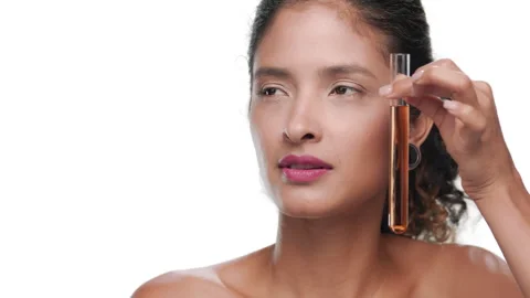 Latin model dark curls moves orange test tube along her face Stock Footage 343052777