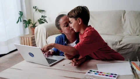 Latin mother work on computer while child son is painting with watercolor Stock Footage 250983926