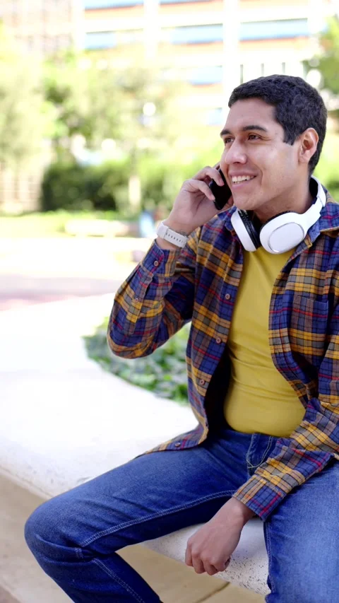 Latin student using phone sitting in the campus Stock Footage 258325415