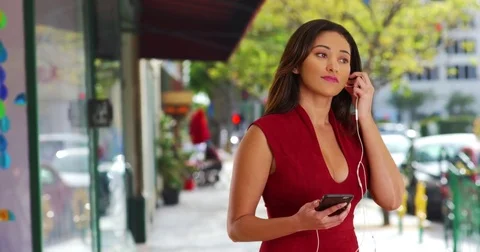 Latina female listening and dancing to music on cell phone on downtown street Stock Footage