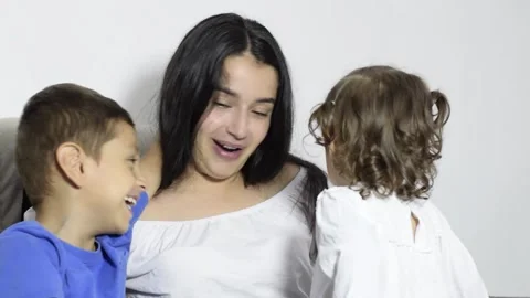 Latina mom talks and laughs a lot with her two children on the sofa, affect.. Stock Footage 332877520