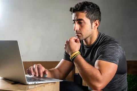 Latino coach working on computer to prepare workout routine in gym Stock Photos