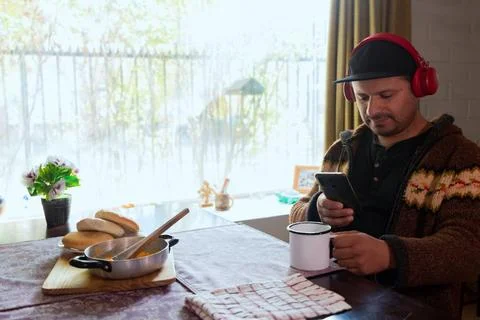 Latino man eats breakfast while checking his cell phone Stock Photos