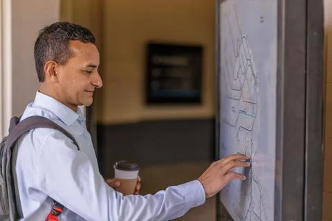 Latino man looking at train map at train station. Stock Photos