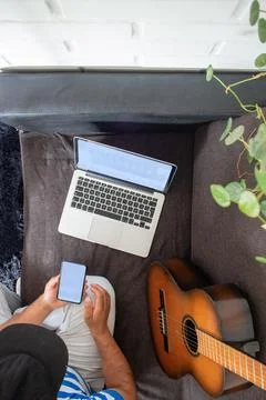 Latino man looks for an online tutorial to learn how to play the guitar Photos