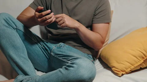 Latino man scrolling on smartphone while sitting on sofa Stock Footage 319219885