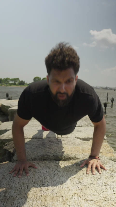 Latino Man's Dynamic Push-Ups on Ocean Rocks in Vertical Video Stock Footage 246387874
