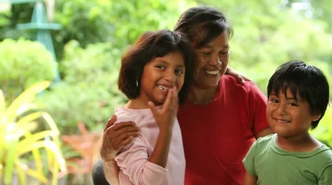 Latino mother and two children pose to camera outdoors, lovinly and smiling Stock Footage