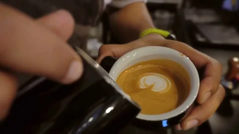 Latte art in black mug. Drinking roasted black coffee in the morning. 動画素材 334648316