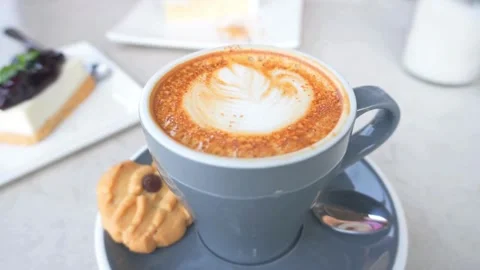 Latte art coffee in a cup and dessert on a table of cafe. Vídeo Stock 334648859