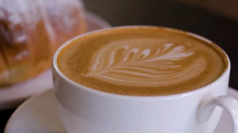 Latte art coffee in a cup and dessert on a table of cafe. Stock Footage 334648940