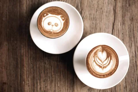 Latte art featuring a panda and leaf design on wooden table surface Stock Photos