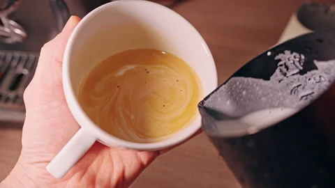 Latte Art Pattern Appearing In Fresh Coffee Cup While Milk Is Carefully Poured C Video stock 330542190