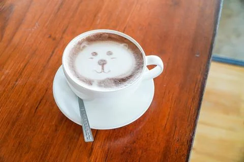 Latte art in the shape of a bear on a coffee table on a wooden table. Stock Photos