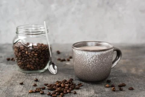 Latte in a ceramic cup and jar with coffee beans on the table. Time for a b.. Stock Photos