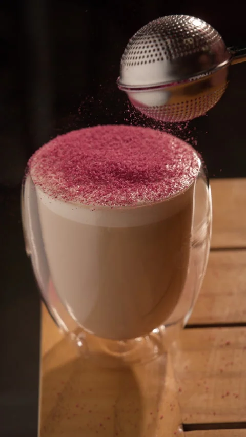Latte coffee in a doubled-walled glass sifted with pink raspberry powder Stock Footage 326439121