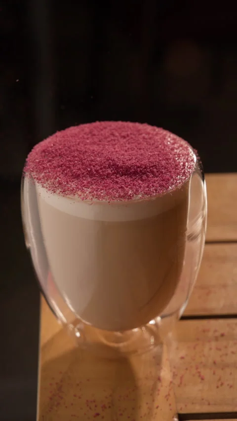 Latte coffee topped with pink raspberry powder sifted over silky steamed foam in Stock-Footage 326438720