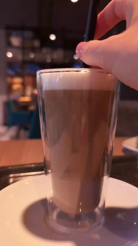 Latte macchiato with straw in cozy coffee shop Stock Footage 276544236