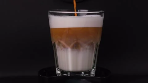 Latte is poured into a glass on a black background close-up Stock Footage 247957976