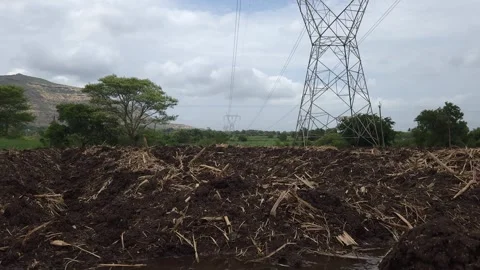 Lattice Structure of an Electricity Pylon Rising Above Heavily Furrowed Farming  Stock-Footage 337180053