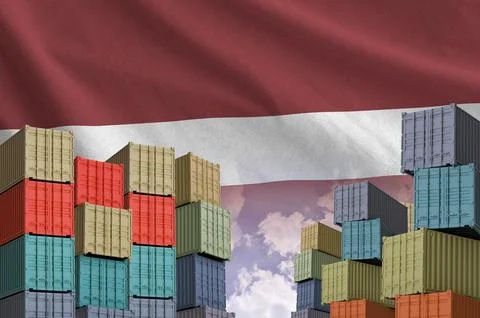 Latvia flag and big stack of shipping cargo containers in docks with sky Foto stock