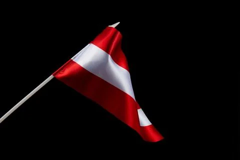 The Latvian flag on a black background is developing and flying in the wind Stockfoto's