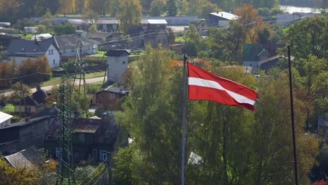 The Latvian Flag Flutters in the Wind High Above a Rural Village. Video stock 306401408