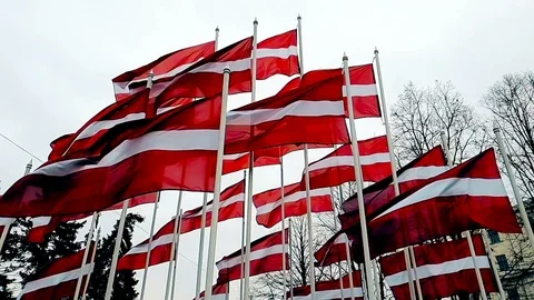 Latvian flags attached to a pole waving in the wind, the skyline of Riga Stock Footage 122189706