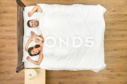 The laugh couple lay on the bed. View from above Stock Photos