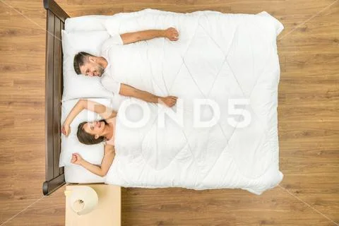 The laugh couple lay on the bed. View from above Stock Photos