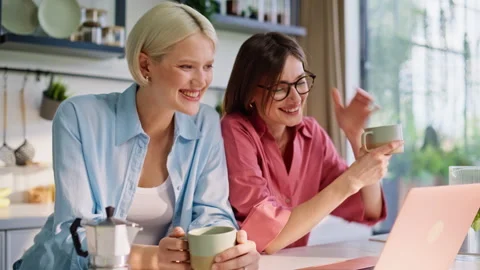 Laughing besties video calling computer in kitchen enjoying morning closeup Stock Footage 335104174