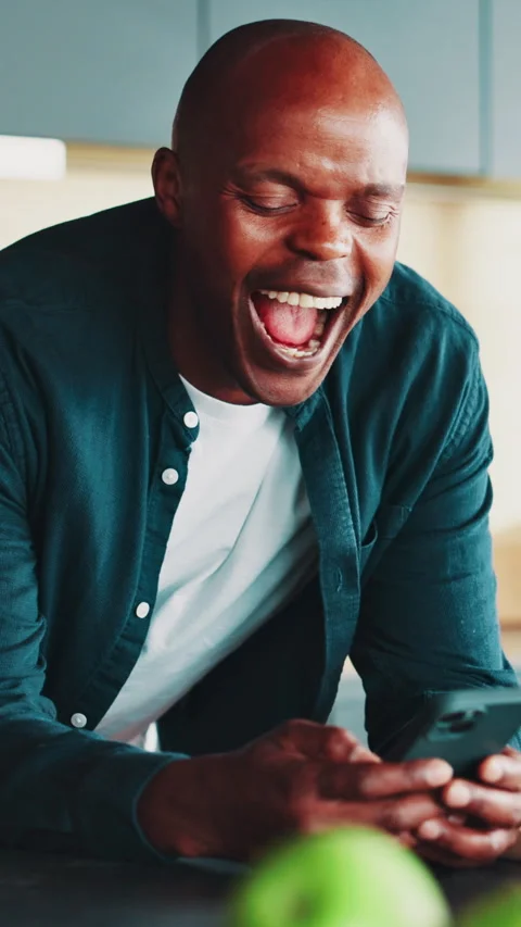 Laughing, black man and reading with phone in kitchen, watch funny video and Stock Footage 321521283