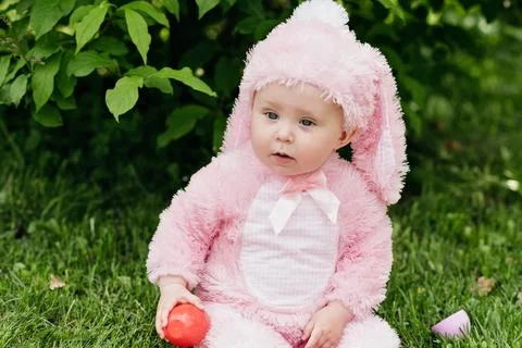 Laughing child at Easter egg hunt baby in pink bunny costume Foto stock