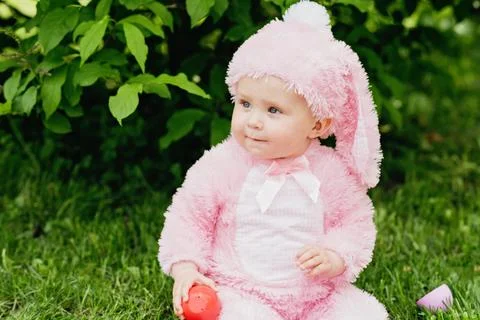 Laughing child at Easter egg hunt baby in pink bunny costume Stock Photos