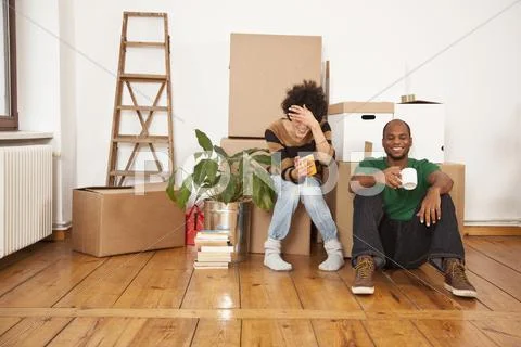 A laughing couple taking a coffee break while moving house Stock Photos