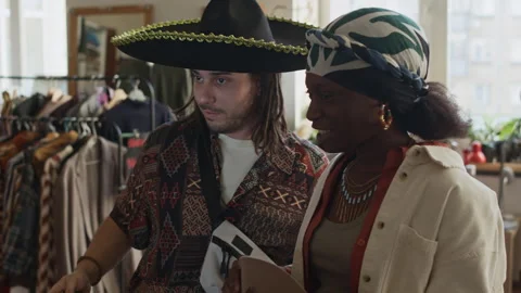 Laughing Diverse Couple Trying on Silly Vintage Hats at Second Hand Outlet Vídeo Stock 327813469